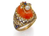 un gros plan d'une bague en or sertie d'une pierre orange et d'une perle