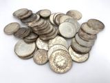 a pile of old silver coins on a white surface