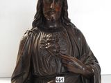 une statue de Jésus assis sur une table près d'un mur blanc