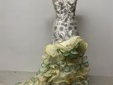 robe à volants jaune et verte sur un mannequin, avec un mur blanc en arrière-plan