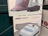 deux boîtes de chapeaux Cricut et une presse à chapeaux posées sur un comptoir