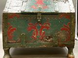 un coffre vert orné de motifs rouges, posé sur une table