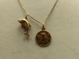 a close up of a necklace with a dolphin and a coin on it