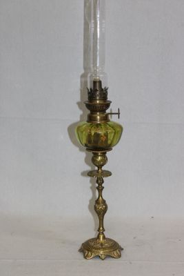 une lampe à huile ancienne en laiton, surmontée d'un abat-jour en verre vert