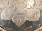 a silver plate with a design on it on a table