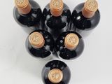 six bottles of wine are arranged in a triangle on a white surface