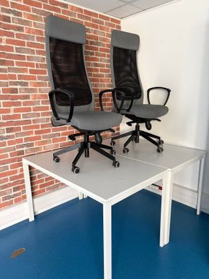 deux chaises de bureau posées sur une table devant un mur de briques