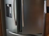 un grand réfrigérateur en acier inoxydable dans une cuisine au sol carrelé