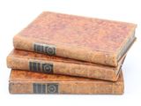 trois vieux livres empilés sur une surface blanche
