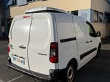 une camionnette blanche garée sur un parking devant un immeuble