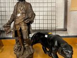 une statue représentant un homme et un chien posée sur une table