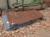 a metal grate laying on the ground next to a pile of wood