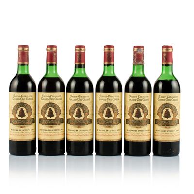 six bottles of wine are lined up on a white surface