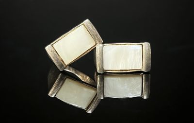 deux boutons de manchette en argent et nacre sur un fond noir