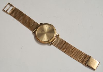 a close up of a gold watch on a white surface