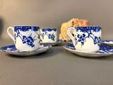 two blue and white cups and saucers with a piece of cake in the background