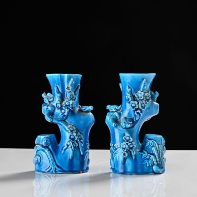 two blue vases sitting on a table with a black background