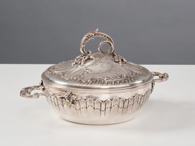 une cocotte en métal argenté munie de poignées, posée sur une table