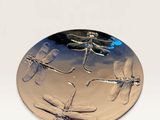 silver plate with dragonflies on it sitting on a white surface