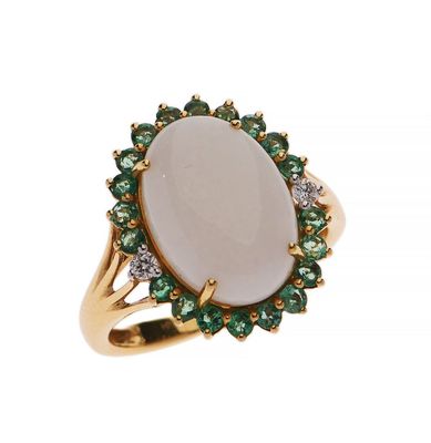 a close up of a ring with a white stone surrounded by green and white stones