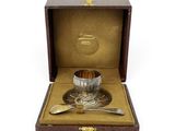 une photo représentant une assiette en argent avec une cuillère et un repose-cuillère dans une boîte