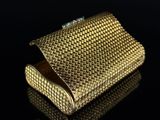 a close up of a gold purse on a black surface