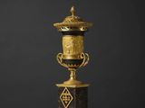 un vase doré et noir posé sur une table blanche