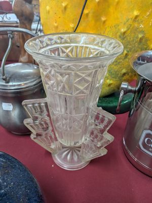 un vase en verre posé sur une table, à côté d'autres objets en verre