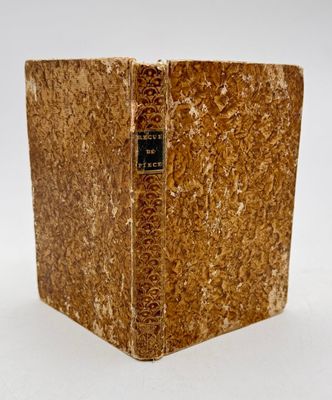 un vieux livre posé sur une table blanche à côté d'un mur blanc