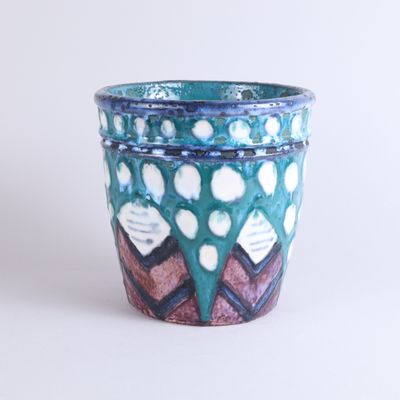 un vase bleu orné d'un motif sur un fond blanc