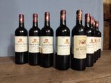 six bottles of red wine are lined up on a wooden table
