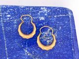 une paire de boucles d'oreilles bleues et dorées posées sur une plaque de marbre bleu