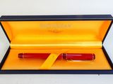 une image représentant un stylo-plume rouge dans une boîte jaune
