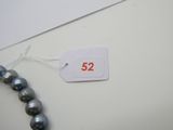 une étiquette portant le chiffre 52, à côté d'un collier de perles