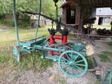 un petit tracteur vert avec un réservoir rouge à l'arrière