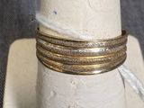 une pile de trois bagues en or posée sur un porte-bagues