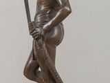 bronze statue of a man with a bow on a wooden table