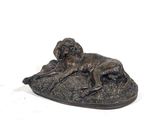 bronze statue of two dogs laying on a rock on a white background