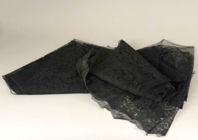 three pieces of black lace on top of a white surface