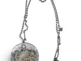 a close up of a necklace on a white surface with a tassel