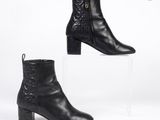 une paire de bottines en cuir noir posées sur un socle en acrylique transparent