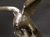 a bronze statue of a bird with a fish in it ' s beak