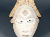 a close up of a wooden mask with a hat on top