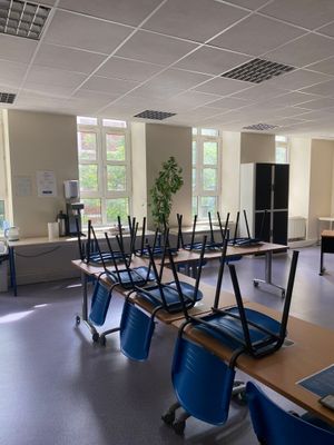 tables and chairs in a classroom with laptops on top of them