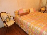 a bed with a colorful comforter and a chair in the corner