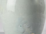 a green vase that has a bird on the top of it