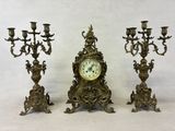 three candles and a clock sitting on a table