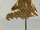 brass eagle head sculpture on a black marble base on a white background