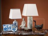 une table sur laquelle se trouvent une lampe, un vase, une assiette et un oiseau