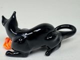 a black cat figurine sitting on a white surface